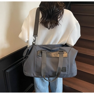 Detail of gray travel bag with durable nylon fabric, leather handles and brand logo
