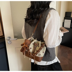 Detalle del bolso tipo cubo de lona retro con bordado floral y colgante de oso