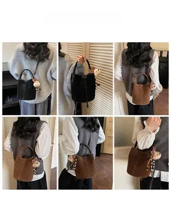 Detalle del bolso de ante tipo cubo en marrón y negro con un lindo colgante de oso