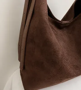 Close-up of soft dark brown suede fabric texture and adjustable strap on bucket bag