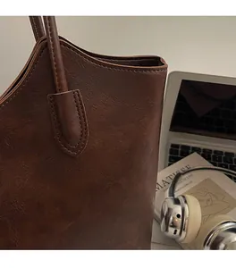 Detail of dark brown lychee grain leather tote bag with neat stitching and handles