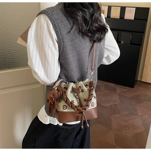Detalle de bolso tipo cubo de lona con bordado floral y remates de cuero