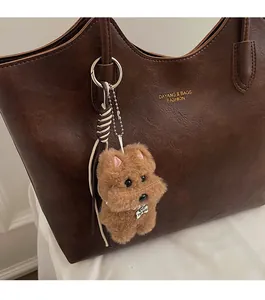 Close-up of brown lychee grain leather tote with plush dog charm and pearl detail