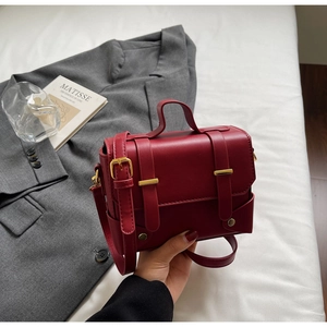 Detail of burgundy leather satchel with metal buckle and adjustable shoulder strap