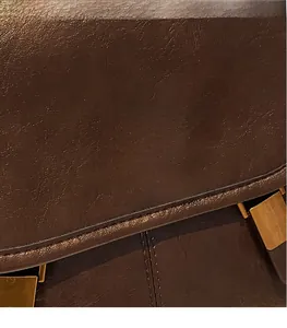 Detail of vintage brown leather backpack featuring a textured gold twist lock closure hardware