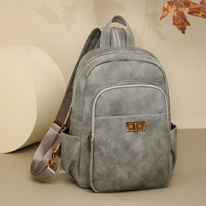 Detail of grey faux leather backpack featuring bronze twist lock and front zipper pocket