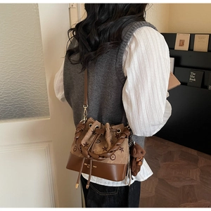 Detalle del bolso tipo cubo vintage marrón con estrellas y cordón en un entorno hogareño