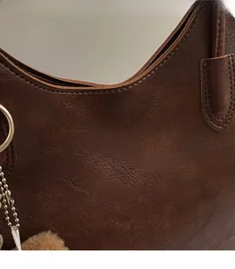 Detail of dark brown tote bag showing pebbled leather texture and gold logo branding
