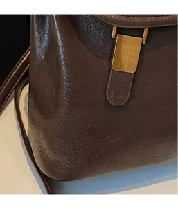 Detail of dark brown wax leather texture and vintage gold metal clasp on the backpack