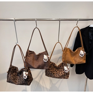 Détail de grands sacs fourre-tout à imprimé léopard et daim avec pendentifs peluche