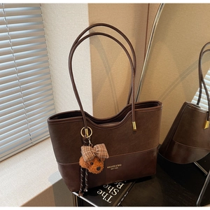 Dettaglio della borsa tote marrone vintage con texture patchwork e ciondolo a orsetto