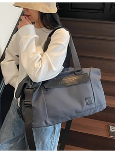 Large capacity dark grey travel duffel bag with leather accents on a wooden staircase