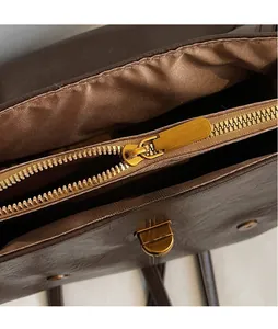 Detail showing smooth gold zipper and striped fabric lining inside a brown leather backpack