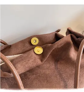 Détail du fermoir magnétique doré sur un sac cabas vintage en daim marron foncé