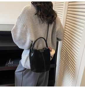 Detalle de bolso cubo negro mate con costuras blancas y colgante de peluche suave