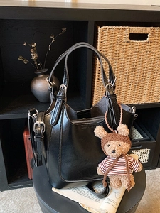 Black glossy bucket bag with teddy bear charm and adjustable shoulder strap