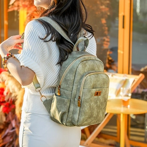 Detail view of vintage green leather backpack showing textured finish and side pocket on model