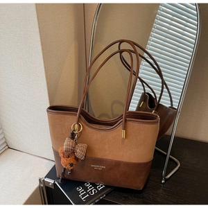 Dettaglio della borsa tote patchwork vintage con ciondolo a orso e finitura marrone