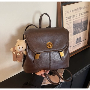 Detail of vintage brown leather backpack with golden swivel lock and bear charm