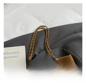 Detail van bruine gewatteerde shopper met gouden ketting en witte pluche hanger