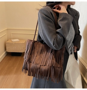 Dettaglio delle nappe in pelle scamosciata multistrato su una borsa marrone stile boho