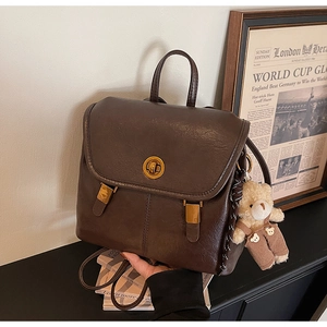 Detail of vintage brown leather backpack with golden rotary lock and cute teddy bear charm