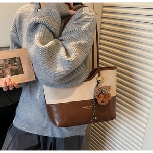 Dettaglio di una borsa tote patchwork beige e marrone con grazioso ciondolo a orsetto