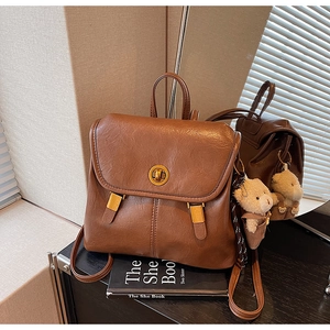 Close-up of caramel brown leather backpack with metal twist lock and plush bear pendant