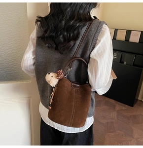Detalle del bolso de ante marrón con un colgante de osito de peluche y correa delgada