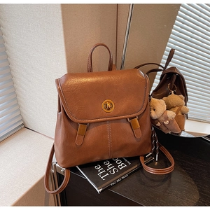 Close-up of vintage brown PU leather backpack texture with metal clasp and bear charm