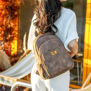 Detail of vintage brown backpack with metallic turn-lock and side pocket on white top