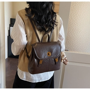 Detail of dark brown vintage backpack with gold turn-lock and cute plush bear charm