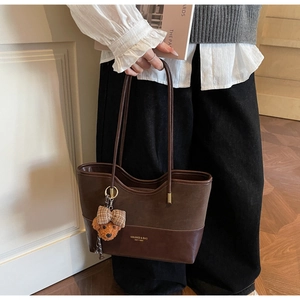 Dettaglio della borsa tote vintage con patchwork bimateriale e ciondolo a forma di orsetto