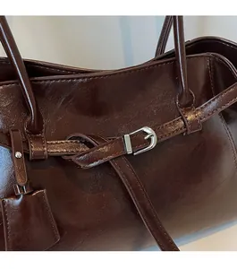 Detail of dark brown glossy oil wax leather bag with silver buckle and texture