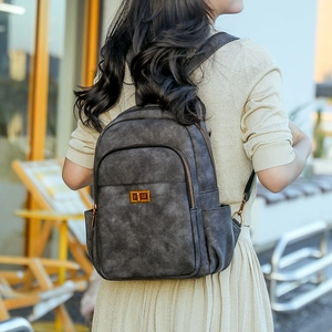 Close-up of vintage dark grey PU leather backpack with gold metal twist lock and zipper