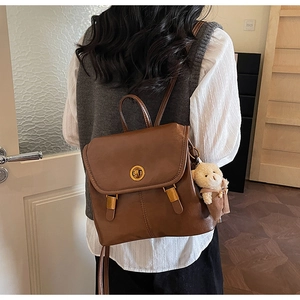 Detailed back view of vintage brown backpack with gold metal buckle and cute bear charm