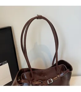 Detail of slim brown leather straps and adjustable metal buckles on retro tote bag