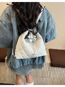 Detail of white quilted tote bag with star charm, tassel puller and chain shoulder strap