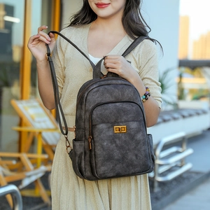 Detail of dark gray vintage faux leather backpack with gold twist lock and side pockets