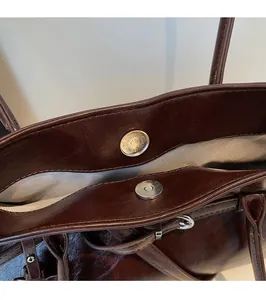 Detail of the magnetic buckle closure and herringbone lining on a brown vintage tote bag