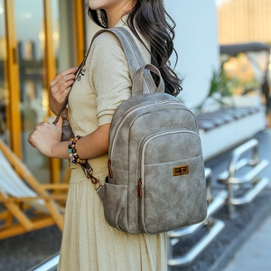Detail of vintage gray backpack with matte leather texture and gold twist-lock closure