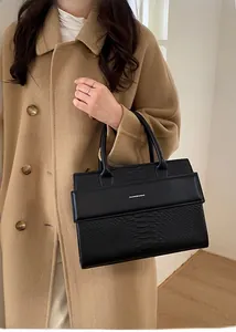 Fashionable black snake-embossed leather tote bag held by a model in a wool coat