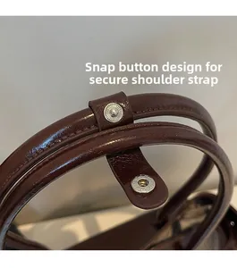 Close-up of vintage brown tote bag showing the YKK snap button and durable leather texture