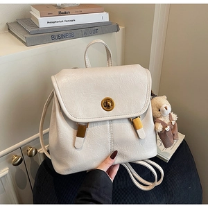 Detail of cream vintage backpack with gold twist lock and cute teddy bear charm