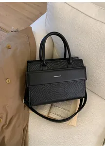 Close-up of black crocodile embossed tote bag with unique patchwork and metal logo