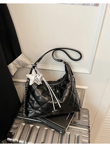 Detail of a black quilted hobo bag with silver star charms and metal logo on book