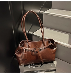 Detail of dark brown vintage tote bag with buckles on a staircase setting