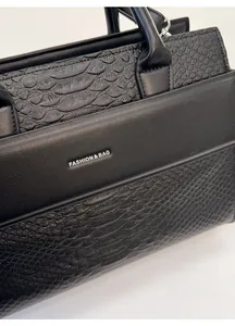 Close-up of black crocodile pattern texture and silver logo plate on the tote bag