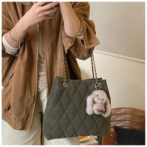 Detailoverzicht van donkergroene gewatteerde shopper met gouden ketting en pluche konijn