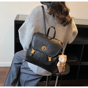 Detail of black vintage backpack with golden twist lock and a cute plush bear charm